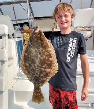 Proud young angler holds up trophy size flounder.